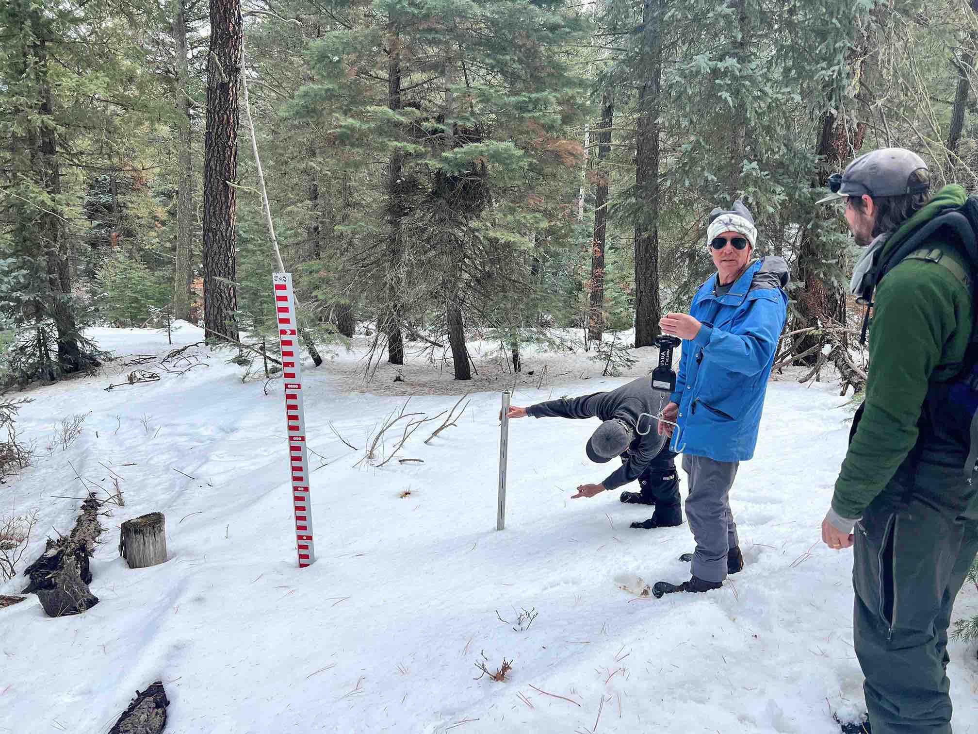 Image of three men in snow doing research and measurements